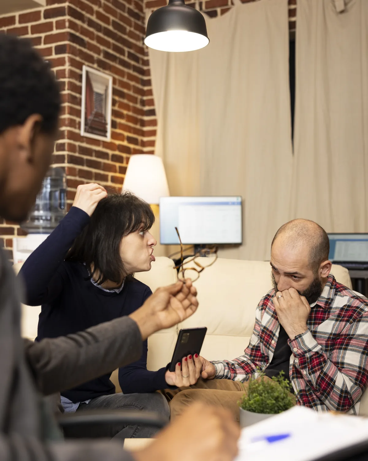 A mediator standing behind a couple seated at a table, each turned away from the other.